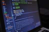 Close-up of a computer screen displaying programming code in a dark environment.