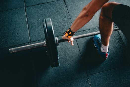 Close-up of a person lifting a barbell in an indoor gym, focusing on strength training.